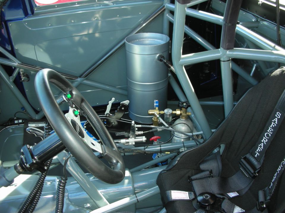 Racing car interior with roll cage, racing seat, steering wheel, and nitrous oxide tank
