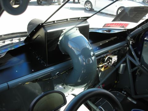 1998 Ford Crown Victoria - The interior of a race car is visible, a prominent grey air intake tube and a protective roll cage structure.