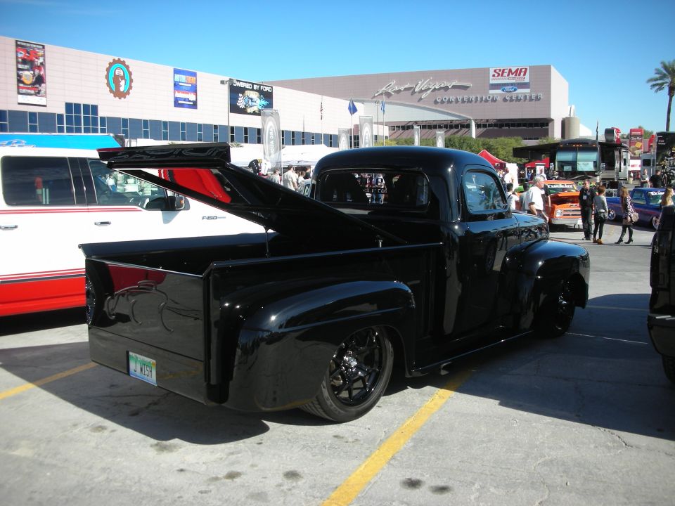 Black custom pickup truck with lowered suspension and custom wheels, parked at an outdoor event