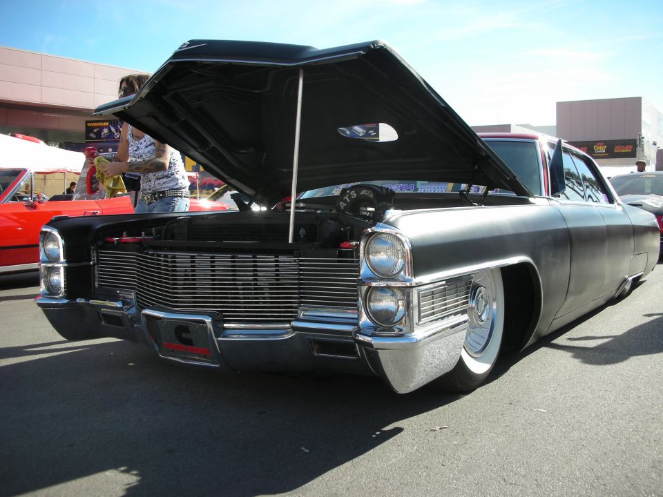 Black Cadillac with hood open, chrome grille, and whitewall tires