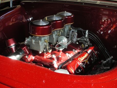 1998 Ford Crown Victoria - Close-up of a custom Oldsmobile Rocket engine with a high-gloss red finish and multiple carburetors.