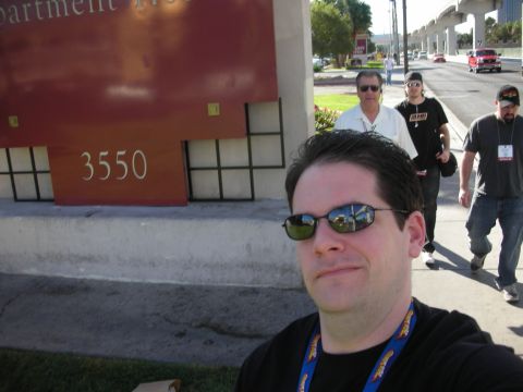 1998 Ford Crown Victoria - A group of people walk along a sidewalk next to a building with the number 3550 visible, while a red truck drives by in the background.