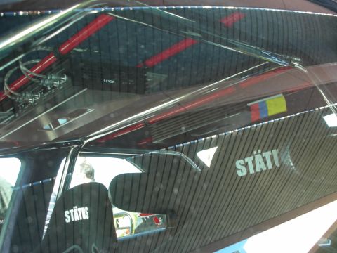 1998 Ford Crown Victoria - The interior of a modified vehicle shows a roll cage, an audio amplifier, and seats with prominent 'STATUS' branding.