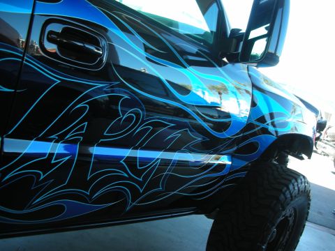 1998 Ford Crown Victoria - A custom-painted truck with intricate blue flame graphics covers its side panel.