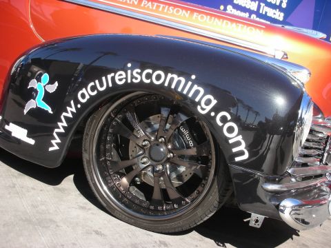 1998 Ford Crown Victoria - A close-up of a customized car fender shows the website www.acureiscoming.com and large aftermarket wheels.