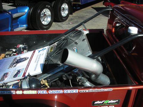 1998 Ford Crown Victoria - Custom truck bed contains engine parts and a sign for a fuel saving device.