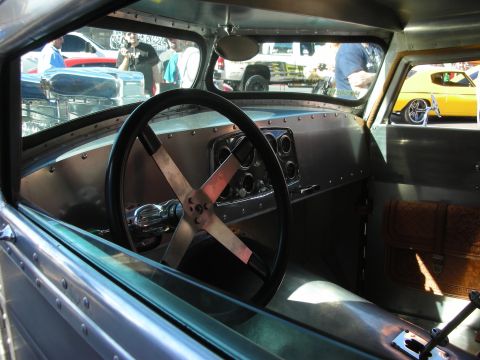 1998 Ford Crown Victoria - The interior of a custom hot rod features a metal dashboard and a unique steering wheel, with other vehicles seen through the windows.