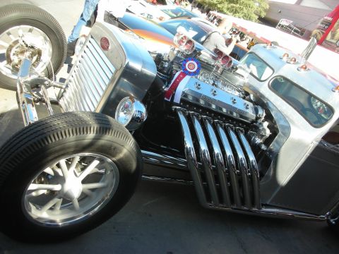 1998 Ford Crown Victoria - A custom hot rod is displayed with its powerful V12 engine prominently featured, complete with chrome exhaust pipes.