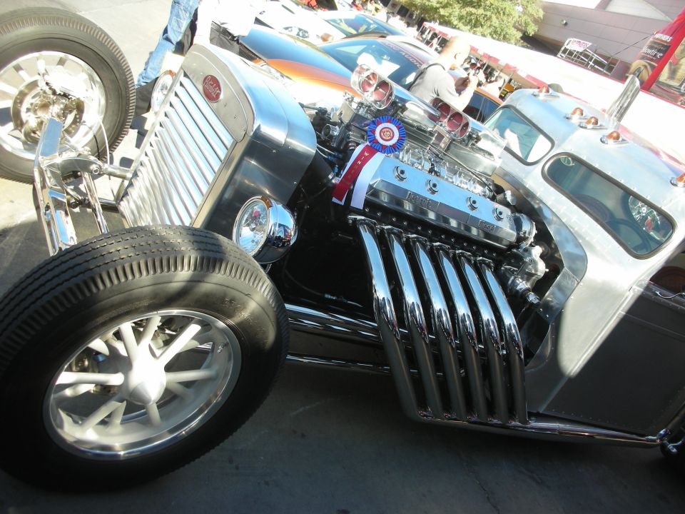Hot rod with exposed V12 engine, chrome grille, and large front wheels