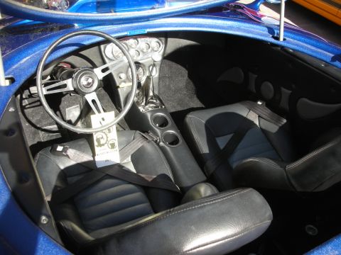 1998 Ford Crown Victoria - The interior of a blue car features black bucket seats with racing harnesses and a classic steering wheel.