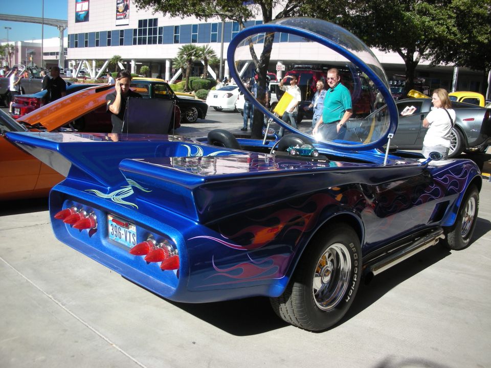 Customized blue car with flame decals, bubble canopy, and red taillights, seen from the rear