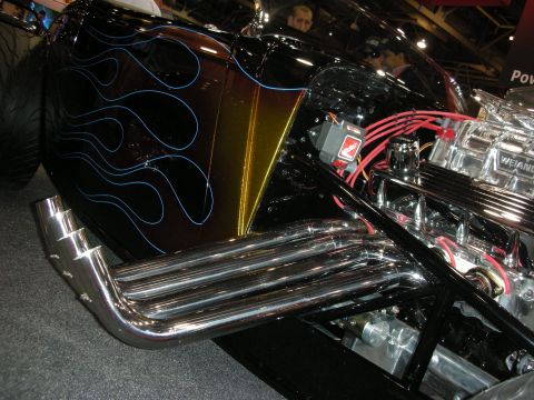 1998 Ford Crown Victoria - A custom hot rod features a black paint job with blue flames, chrome exhaust headers, and a visible V8 engine.