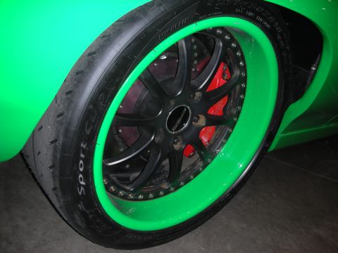 1998 Ford Crown Victoria - A close-up view of a custom wheel and tire assembly on a bright green vehicle.
