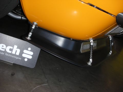 1998 Ford Crown Victoria - A black front splitter is attached to an orange car body with metal hardware and supports.