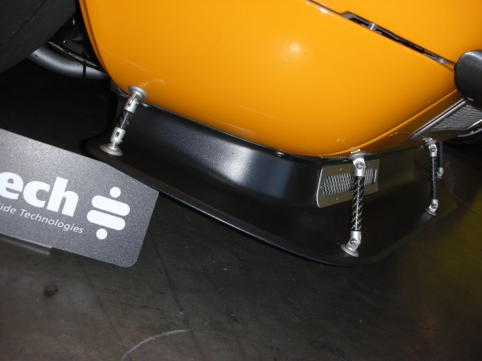 close-up of orange car body and black front splitter with metal supports