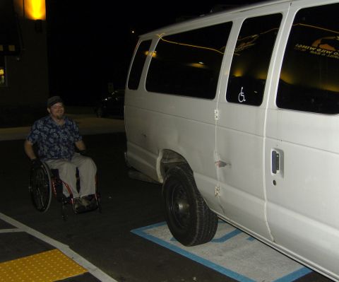 2007 Ford Mustang - A person in a wheelchair is next to a white van parked in a designated accessible spot.