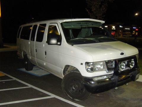 2007 Ford Mustang - White Ford E-Series van with a bull bar and auxiliary lights parked in a lot at night.