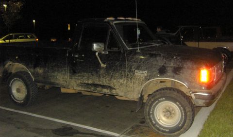 2007 Ford Mustang - A muddy black Ford F-150 pickup truck is parked at night, with another vehicle visible in the background.