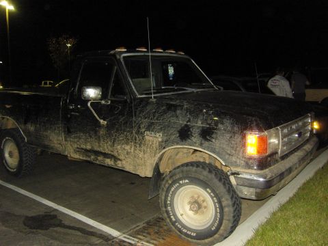 2007 Ford Mustang - This black pickup truck is heavily covered in mud, obscuring its details.