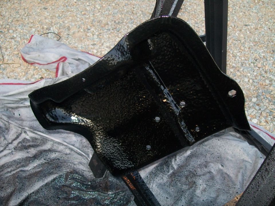 Black painted metal bracket part resting on a shop rag outdoors