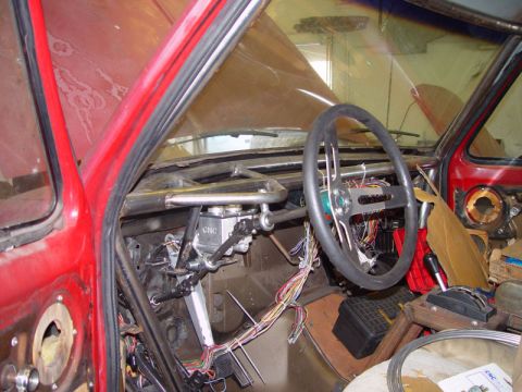 1980 Ford Bronco - The interior of a red vehicle shows extensive modifications, including a roll cage and exposed wiring, suggesting a custom build.