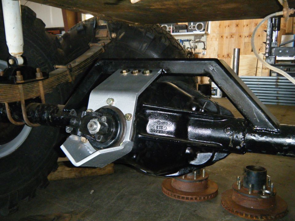close-up of a vehicle's rear axle assembly with suspension components and a black differential housing