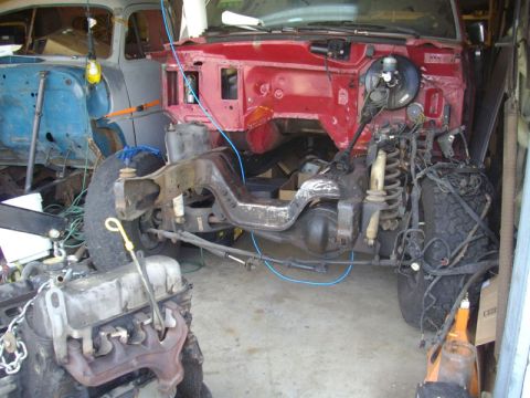 1980 Ford Bronco - Vehicle chassis undergoing disassembly, with a separate vehicle body visible in the background.