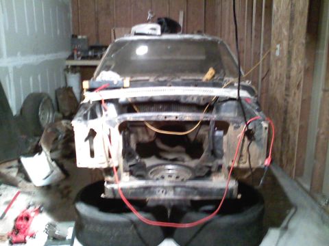 1969 Ford Mustang - The front of a vehicle is disassembled and appears to be undergoing repairs or restoration in a workshop.