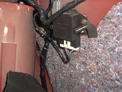 1993 Ford Taurus - Close-up of a car's interior wiring harness and a black module mounted on a red panel.