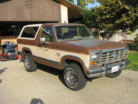 1986 Ford Bronco - This 1986 Ford Bronco features a two-tone brown and tan paint scheme and is parked in front of a garage.