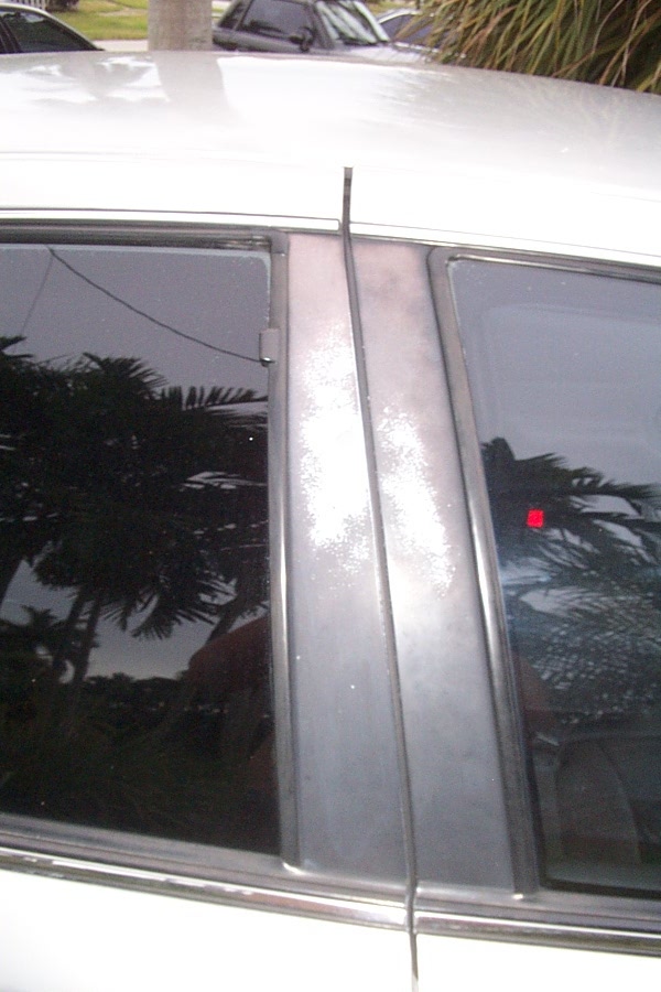 close-up of car's B-pillar and tinted windows, another car visible in background