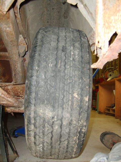 1963 Ford Galaxie - Close-up of a tire and the corroded undercarriage of a vehicle, showing significant rust.