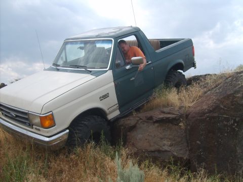 1989 Ford Bronco - This 1989 Ford Bronco is shown off-roading over rocks and dry grass.