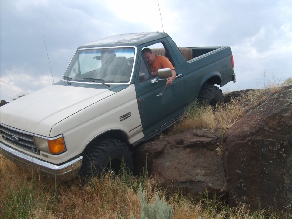 Two-tone green and white 1989 Ford Bronco navigating rocky terrain