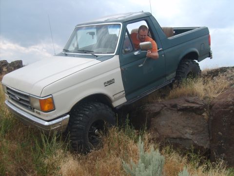1989 Ford Bronco - Ford F-250 Bronco navigating rocky terrain with a driver inside.