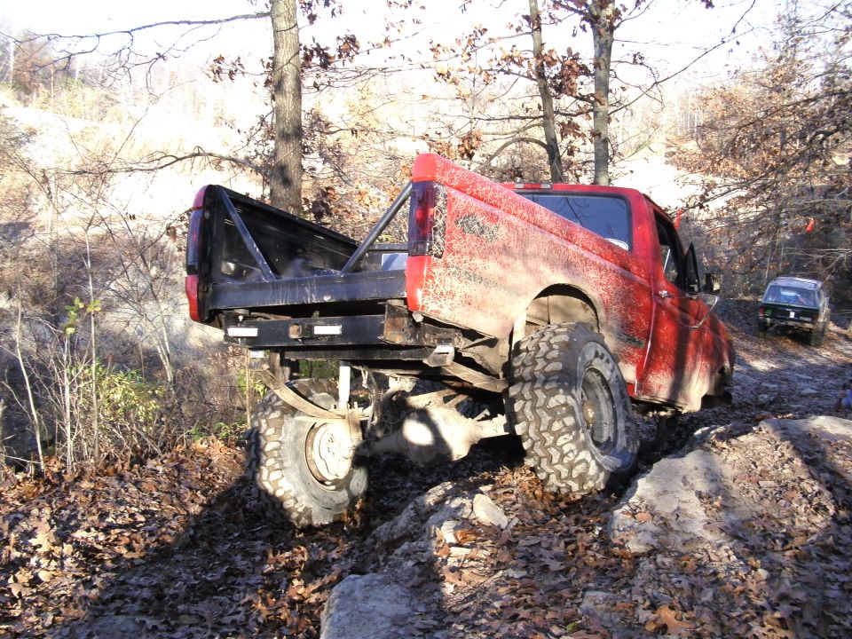 Red 1994 Ford F-250 with flatbed conversion on rocky terrain