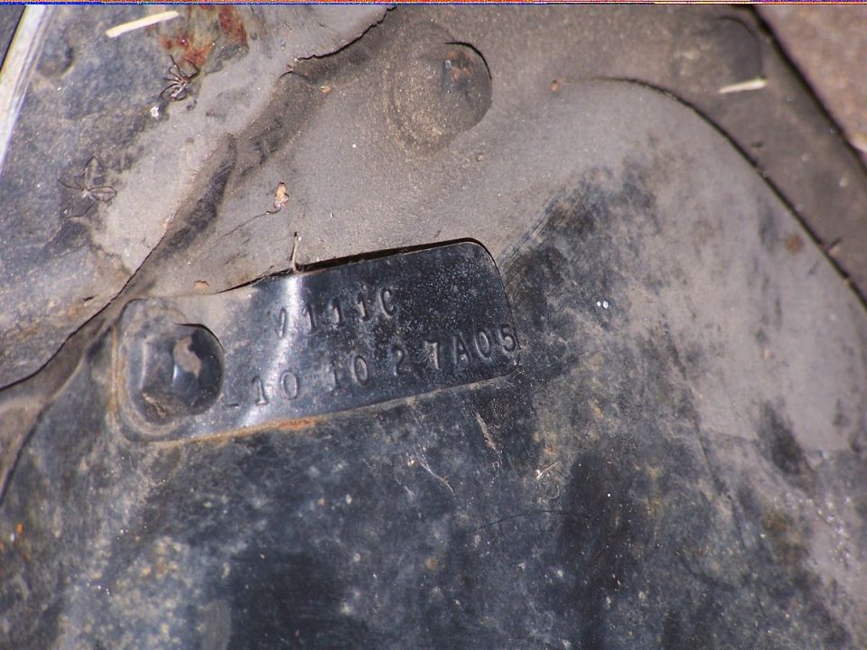 Stamped metal identification tag on a dirty axle housing