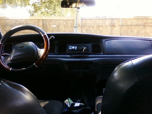 1998 Ford Crown Victoria interior, dashboard with aftermarket radio, wood-trimmed steering wheel, and black seats