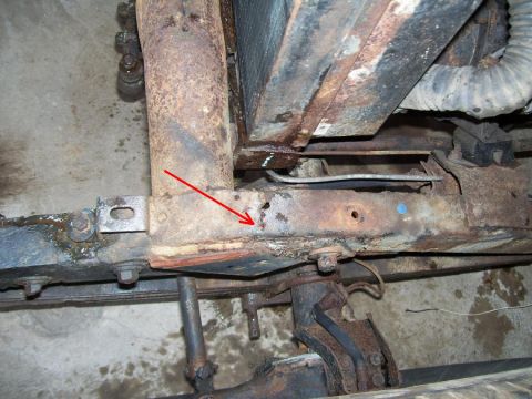 1948 Jeep Wrangler - Close-up view of a heavily rusted vehicle frame section, with a red arrow highlighting a hole.
