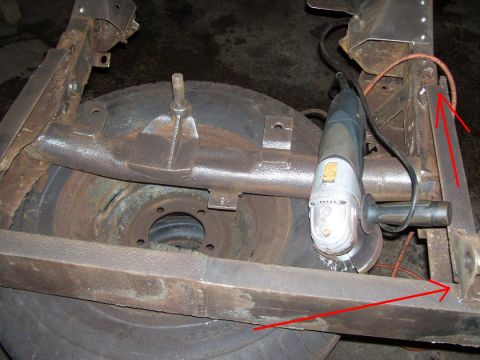 1948 Jeep Wrangler - Close-up of a vehicle's undercarriage, showing frame rust and a spare tire, with an angle grinder present.