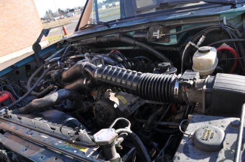 1996 Ford Bronco - The engine bay of a vehicle is shown with various components and hoses.