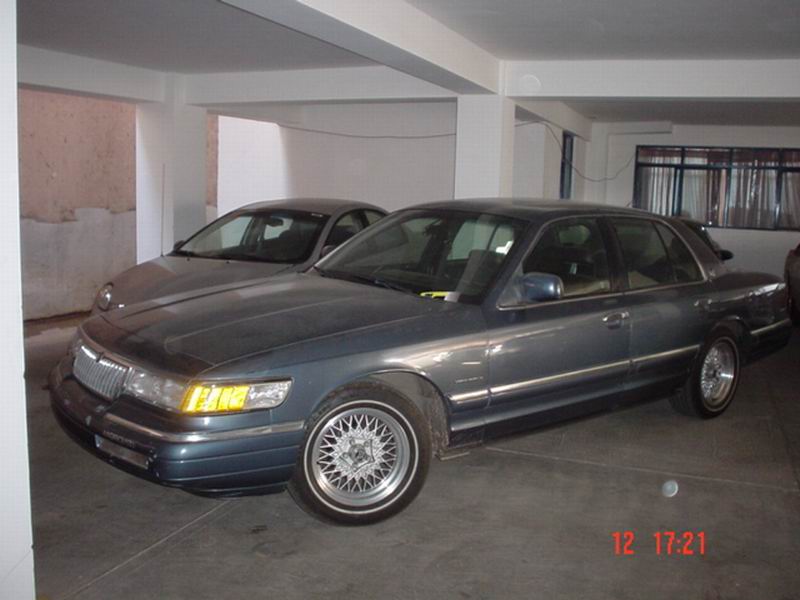 1992 Mercury Grand Marquis parked next to a dark sedan in a garage