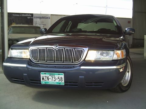 1992 Mercury Grand Marquis - A dark blue Mercury Grand Marquis is shown from the front in a garage. Another vehicle is visible in the background.