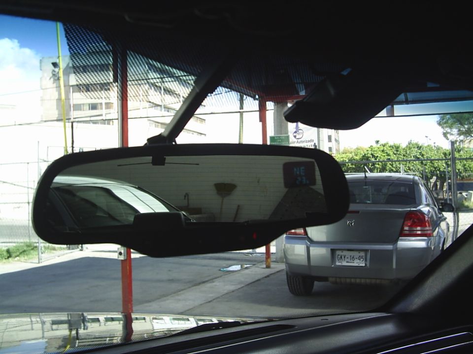 Rear of a silver sedan with a license plate that reads CKV-16-95. Another car is reflected in the rearview mirror