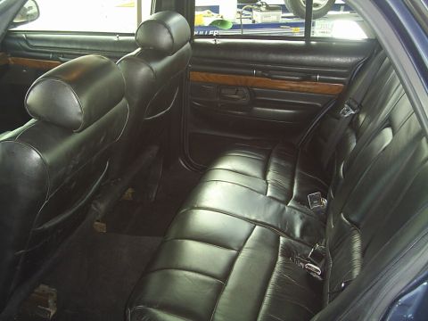 1992 Mercury Grand Marquis - Rear interior view of a 1992 Mercury Grand Marquis, showing the black leather seats and door panels with wood accents.