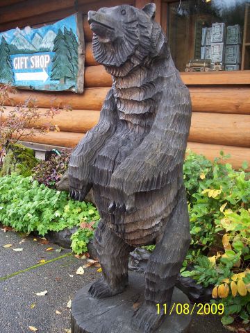 1989 Ford Bronco - A carved wooden bear stands guard outside a gift shop with a sign pointing the way.