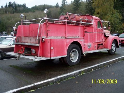 1989 Ford Bronco - A red fire truck is parked in a lot, with another vehicle visible to the left.