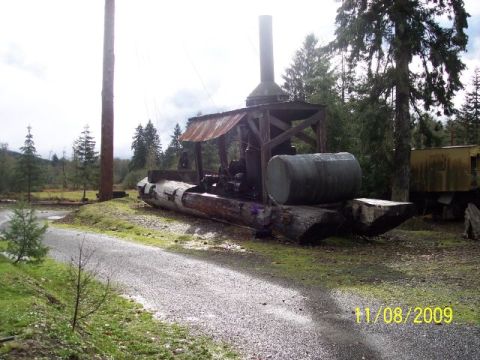 1989 Ford Bronco - A rustic scene old logging machinery with a large log and tank.