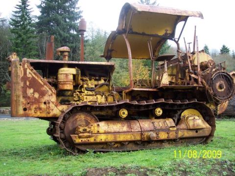 1989 Ford Bronco - An old, weathered bulldozer sits in a grassy field, its yellow paint faded and rusted.
