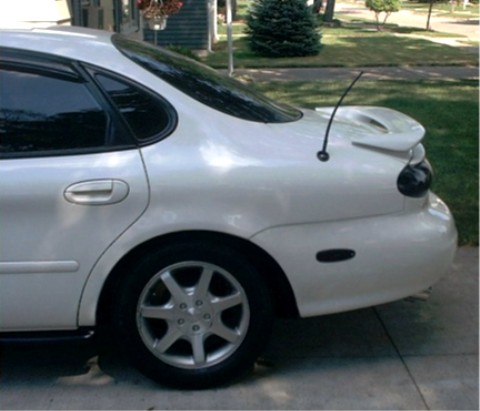 1990 Ford Taurus - Rear view of a white sedan, a spoiler and an antenna. The body style suggests a 1990s model, but it does not appear to be a 1990 Ford Tauru…